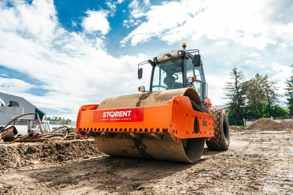Large vibratory roller compactor on a sunny construction site.